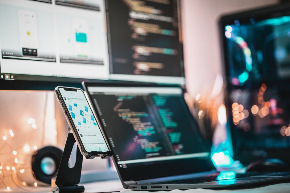 A close-up view of a tech setup with gadgets, coding screen, and smartphone, perfect for tech themes.